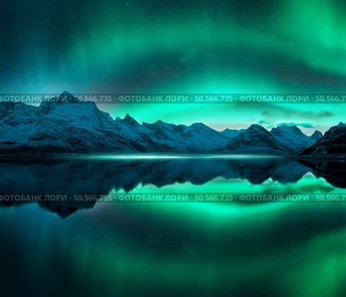 Aurora borealis over the snowy mountains, frozen sea, reflection in water at winter night. Lofoten, Norway. Northern lights and snowy rocks. Landscape with polar lights, starry sky and fjord. Scenery. Стоковое фото, агентство Ingram Publishing / Фотобанк Лори
