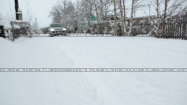 Автомобиль проезжает по снежной деревенской дороге, фокус на переднем плане (2015 год). Редакционное видео, видеограф Кекяляйнен Андрей / Фотобанк Лори