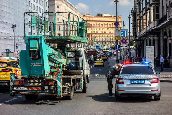 Автовышка Tadano в центре Москвы на Театральной площади остановлена патрульным автомобилем. Водитель вышки вышел из машины и отвечает на вопросы гаишника.(2024)/ A Tadano aerial platform in the center of Moscow on Teatralnaya Square was stopped by a patrol car for violating traffic rules. Редакционное фото, фотограф Iva Noel / Фотобанк Лори