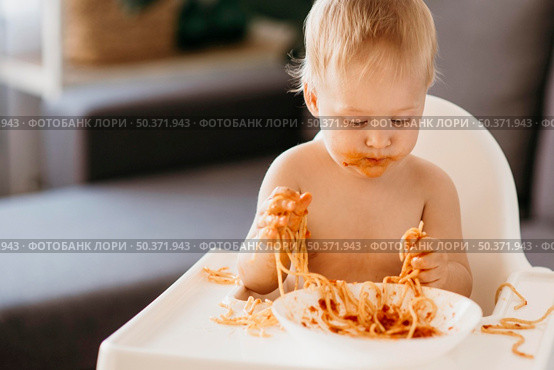baby boy eating pasta his highchair making mess. Стоковое фото, агентство Ingram Publishing / Фотобанк Лори
