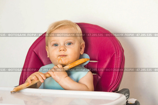 Baby food. The first meal. Feeding the baby. A cute little kid eats vegetables. Healthy food. The child is sitting on a high chair for feeding. Fresh vegetables and fruits. Стоковое фото, фотограф Photojuli / Фотобанк Лори
