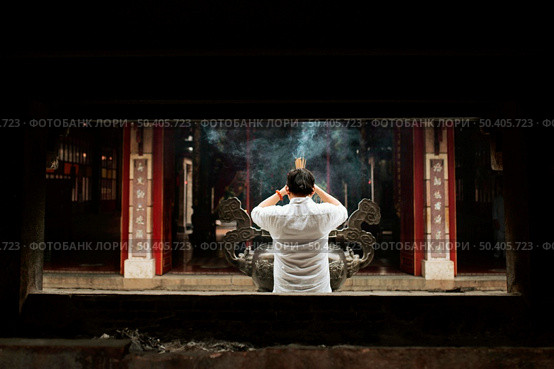 back view man praying temple with burning incense. Стоковое фото, агентство Ingram Publishing / Фотобанк Лори