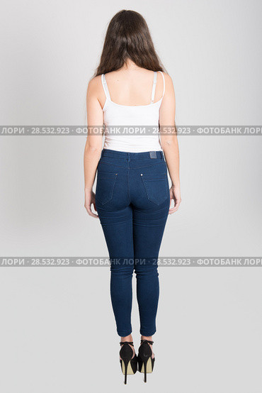 Back view of young woman with long hair wearing white t-shirt and blue jeans on white background. Стоковое фото, фотограф Javier Sánchez Mingorance / Ingram Publishing / Фотобанк Лори