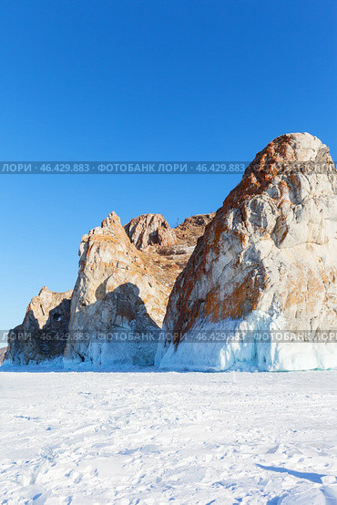 Baikal Lake on sunny February day. View of famous Cape Sagan-Khushun or Three Brothers Cliff - natural landmark of Olkhon Island and tourist destination against background of blue sky on sunny day. Стоковое фото, фотограф Виктория Катьянова / Фотобанк Лори