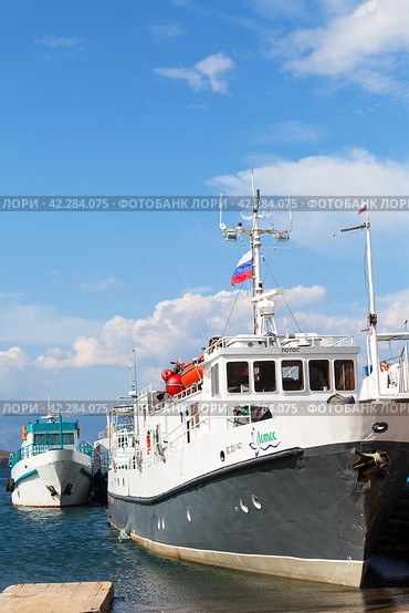 BAIKAL LAKE, SAKHYURTA VILLAGE, IRKUTSK REGION, RUSSIA - August 14, 2023: Ships and yachts at pier on shores of Small Sea on sunny summer day. Village of Sakhyurta is traditionally starting point for water travel around lake. Редакционное фото, фотограф Виктория Катьянова / Фотобанк Лори