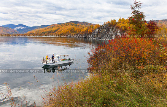 BAIKAL LAKE, SLUDYANKA VILLAGE, IRKUTSK REGION, RUSSIA - September 18, 2022: A family with children travels on a pleasure boat around the famous Cape Shamansky on an autumn day. Редакционное фото, фотограф Виктория Катьянова / Фотобанк Лори