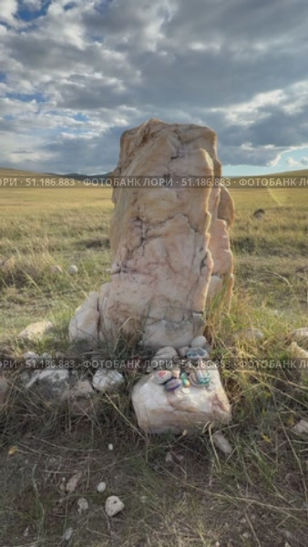 Baikal Lake. Vertical video of offerings and gifts from tourists at sacred marble stone in labyrinth of place of power on Olkhon Island. Tourists leave souvenirs and painted stones as sign of veneration of lake spirits. Стоковое видео, видеограф Виктория Катьянова / Фотобанк Лори
