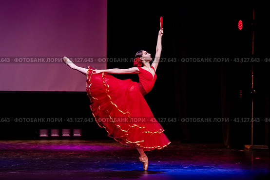Ballerina in a red dress performs a variation from the ballet Don Quixote on the theater stage. Стоковое фото, фотограф Мария Мороз / Фотобанк Лори