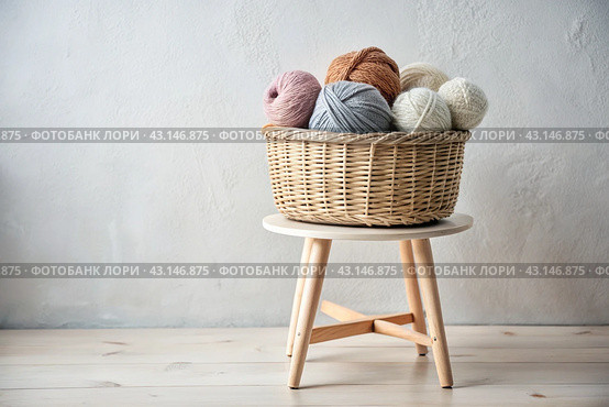 Balls of yarn in a wicker basket in white and beige tones. Needlework, textiles, knitting. Winter season, small business, handmade clothes. Стоковое AI-изображение, AI-художник Photojuli / Фотобанк Лори