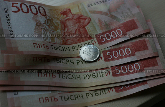 Банкноты номиналом 5000 российских рублей и монета в 1 российский рубль. Стоковое фото, фотограф Юлия Зырянова / ТАСС / Фотобанк Лори