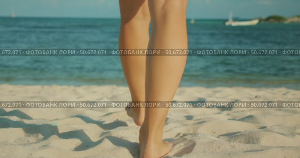 Barefoot woman walks across soft white sand toward the turquoise sea in sunny day. Стоковое видео, видеограф Igor Tichonow / Фотобанк Лори