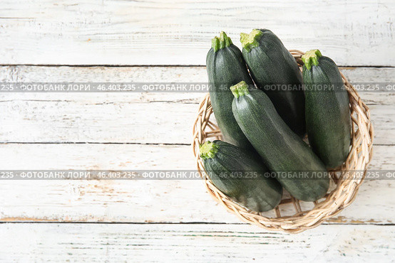 Basket with fresh zucchini squashes on light wooden background. Стоковое фото, фотограф Pixel_shot / Фотобанк Лори