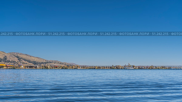 Beautiful blue lake. Reed houses are visible on the shore, boats Balsa de totora are moored, tourist ships. Clear sky. Copy space. Peru. Uros Floating Islands. Lake Titicaca. Стоковое фото, фотограф Вера Ивановна Кубарева / Фотобанк Лори