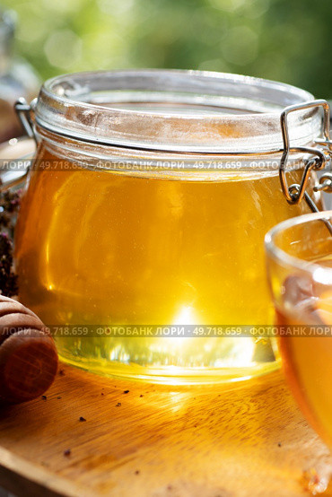 beautiful fresh natural golden  linden honey in big glass jar  at wooden tray in beautiful sunny light. close up. Стоковое фото, агентство Ingram Publishing / Фотобанк Лори