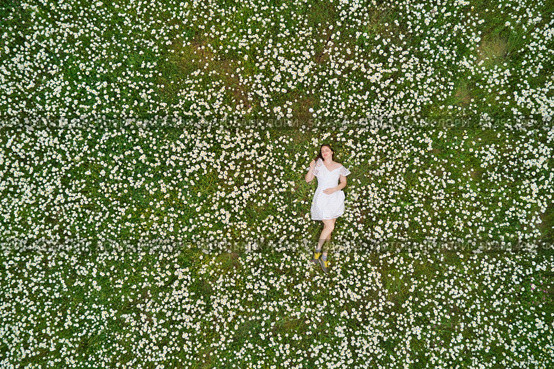 Beautiful girl lies in camomile daisy flower. View from above. Aerial photography. Стоковое фото, агентство Ingram Publishing / Фотобанк Лори