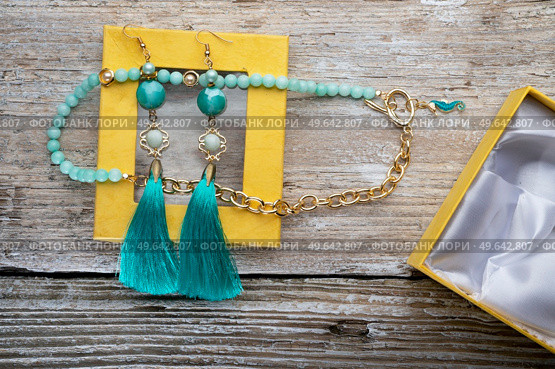 beautiful handmade  turquoise  jewelry with natural gems in yellow box around old style wooden background. close up. fashion concept. Стоковое фото, агентство Ingram Publishing / Фотобанк Лори