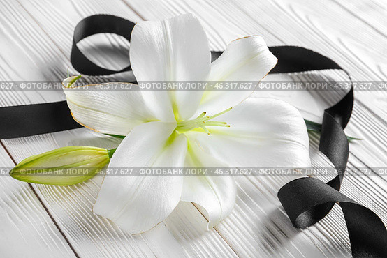 Beautiful lily flowers and black funeral ribbon on white wooden background. Стоковое фото, фотограф Pixel_shot / Фотобанк Лори