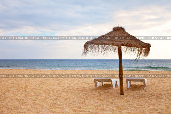 Beautiful sandy deserted beach with an umbrella and deck chairs on the beach. The concept of a summer holiday. Natural sea background. Стоковое фото, фотограф Виктория Катьянова / Фотобанк Лори
