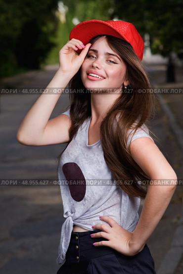 beautiful smiling teen model on street. red cap, grey t-shirt, dark blue shorts. Стоковое фото, агентство Ingram Publishing / Фотобанк Лори