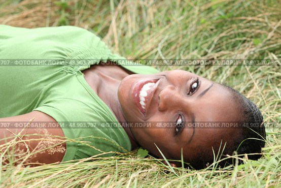 Beautiful smiling woman laying in the long grass. Стоковое фото, агентство Ingram Publishing / Фотобанк Лори
