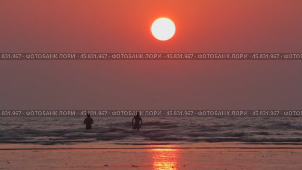Beautiful sunset on the ocean. Silhouettes of people on the shore. Стоковое видео, видеограф Виктор Тихонов / Фотобанк Лори