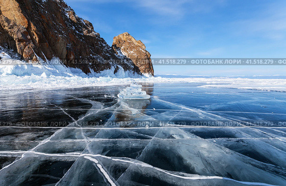 Beautiful winter landscape of frozen Baikal Lake on February. View of famous natural landmark of Olkhon Island - Khoboy Cape or Deva Rock on background of blue sky. Winter travel and outdoor recreation. Стоковое фото, фотограф Виктория Катьянова / Фотобанк Лори