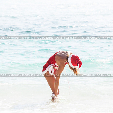 Beautiful woman in Mrs. Claus custume on tropical beach, Christmas vacations concept. Mrs. Claus on tropical beach. Стоковое фото, агентство Ingram Publishing / Фотобанк Лори