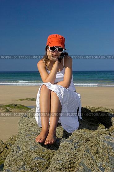 Beautiful woman on the beach with a orange hat and white glasses thinking in something. Стоковое фото, агентство Ingram Publishing / Фотобанк Лори