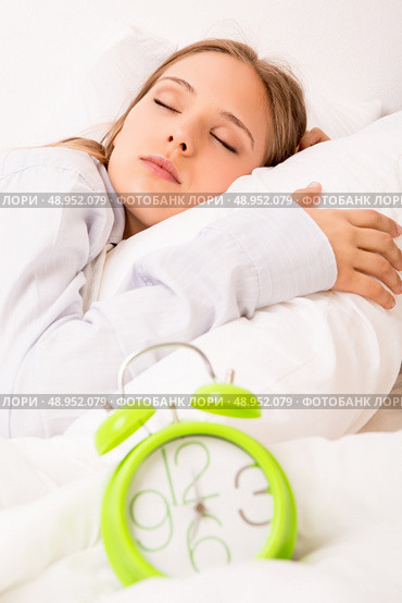 Beautiful woman sleeping with alarmclock on the bed . Стоковое фото, агентство Ingram Publishing / Фотобанк Лори