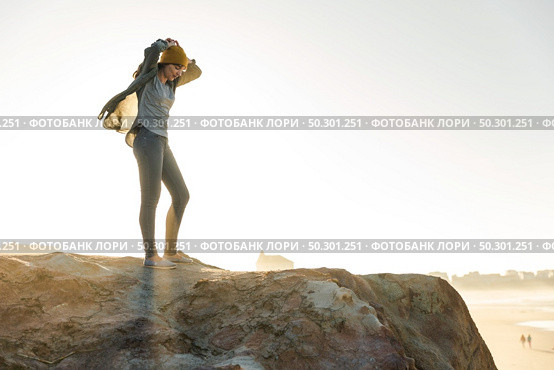Beautiful woman with a yellow cap on a cliff over the beach. Стоковое фото, агентство Ingram Publishing / Фотобанк Лори