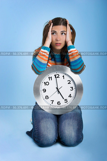 Beautiful women over knees holding a big clock in a blue background. Стоковое фото, агентство Ingram Publishing / Фотобанк Лори