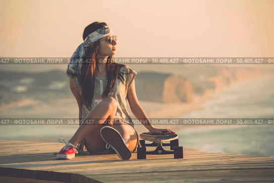 Beautiful young fashion skater girl looking at the sunset. Стоковое фото, агентство Ingram Publishing / Фотобанк Лори