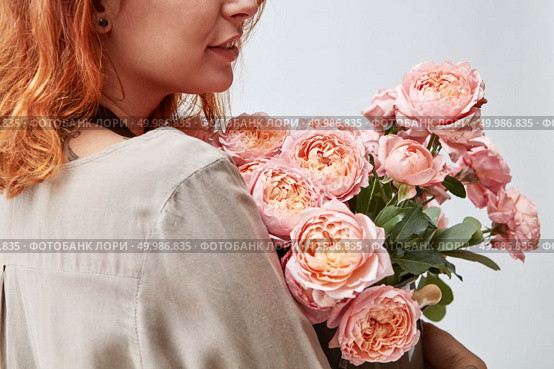 Beautiful young girl with a bouquet of pink roses in a vase. Mothers Day.. Woman holding a vase with fresh pink roses. Стоковое фото, агентство Ingram Publishing / Фотобанк Лори