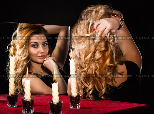 Beautiful young woman with candles looking in the mirror. Стоковое фото, фотограф Art Konovalov / Фотобанк Лори