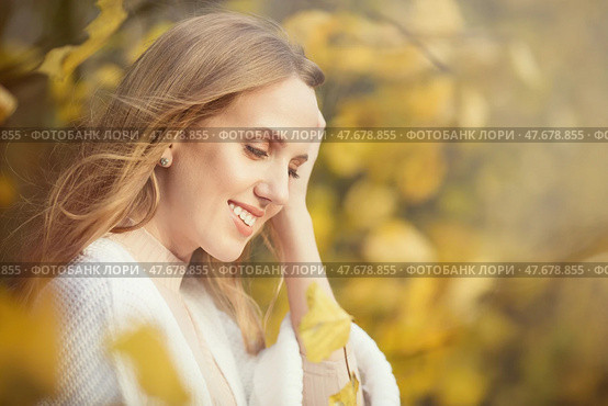 Beautiful young woman with light brown hair in a white sweater on a background of foliage in an autumn park. Portrait of an attractive happy woman among colorful yellow leaves. Fall season. Autumn. Стоковое фото, фотограф Андрей Степанов / Фотобанк Лори