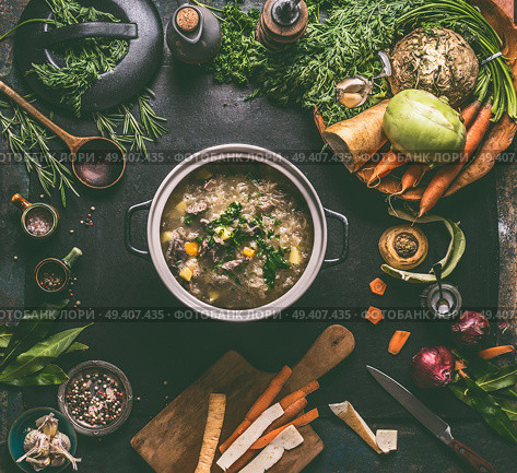 Beef and cabbage soup or stew in cast iron cooking pot on dark background with low carb vegetables, spices ingredients and wooden spoon, top view. Healthy clean low-calorie food and eating concept. Стоковое фото, агентство Ingram Publishing / Фотобанк Лори