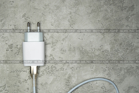 Белый блок питания с кабелем USB на сером фоне. Адаптер питания, зарядное устройство для бытовой электроники. Редакционное фото, фотограф Sergei Gorin / Фотобанк Лори
