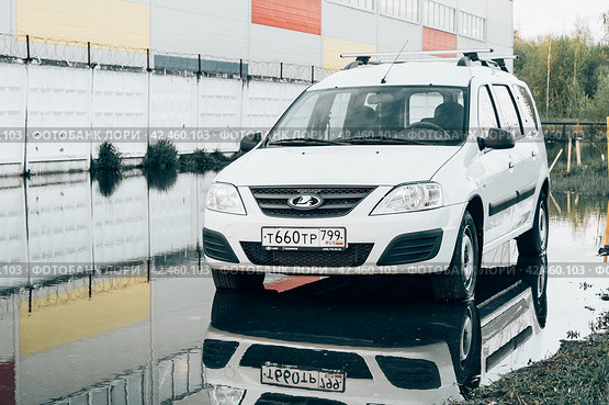 Белый универсал Lada Largus, вид спереди. Автомобиль припаркован в луже (2021 год). Редакционное фото, фотограф Константин Григорьев / Фотобанк Лори