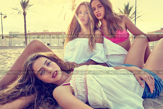 Best friends teen girls together relaxed on a beach sand at sunset. Стоковое фото, агентство Ingram Publishing / Фотобанк Лори