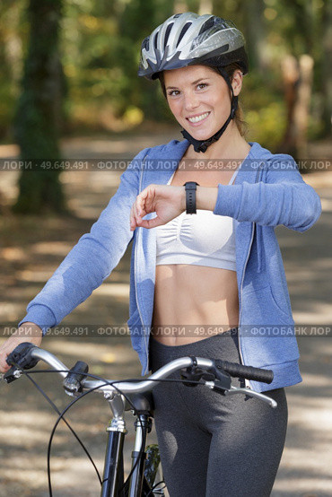 bicyclist girl looking at watch on smart watch. Стоковое фото, агентство Ingram Publishing / Фотобанк Лори