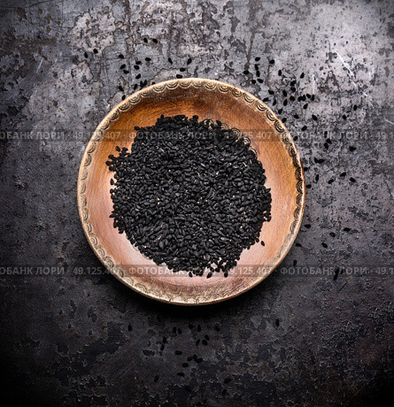Black cumin seeds in rustic bowl on dark vintage background, top view. Nigella sativa seeds. Стоковое фото, агентство Ingram Publishing / Фотобанк Лори