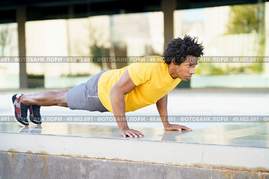 Black man doing triceps dip exercise on city street bench. Fitness, sport, exercising, training and people concept. Black man doing triceps dip exercise on city street bench. Стоковое фото, агентство Ingram Publishing / Фотобанк Лори