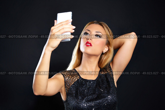 Blond fashion woman smartphone selfie in black background. Стоковое фото, агентство Ingram Publishing / Фотобанк Лори