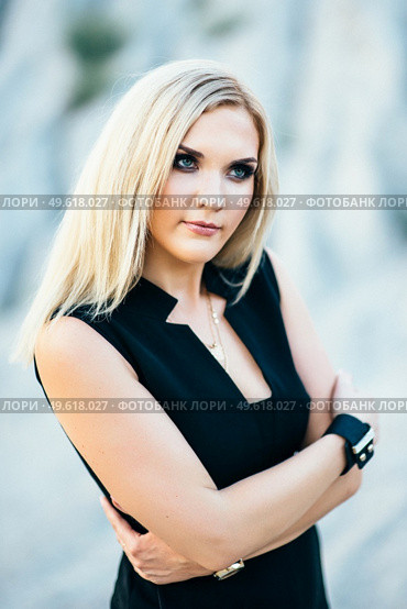 blonde girl in a black trouser suit with blue eyes on the background of a granite quarry from gray rubble. Стоковое фото, агентство Ingram Publishing / Фотобанк Лори