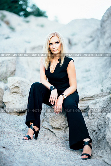 blonde girl in a black trouser suit with blue eyes on the background of a granite quarry from gray rubble. Стоковое фото, агентство Ingram Publishing / Фотобанк Лори