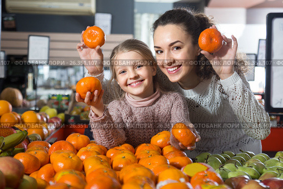 Blonde girl with mother buying mandarins in shop. Стоковое фото, фотограф Татьяна Яцевич / Фотобанк Лори