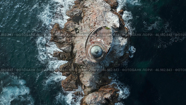 Blue waves beat against stone ledge with lighthouse on sunny day. Стоковое фото, фотограф David Kashakhi / Фотобанк Лори