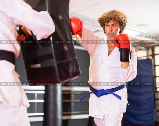 Blue‑belt karateka punching shield in dojo training. Стоковое фото, фотограф Яков Филимонов / Фотобанк Лори