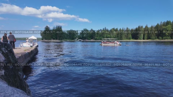 Boating and relaxation on a sunny day on the shore of the Vyborg Bay against the backdrop of green trees - Vyborg, Russia, July 15, 2025. Редакционное видео, видеограф Наталия Попова / Фотобанк Лори
