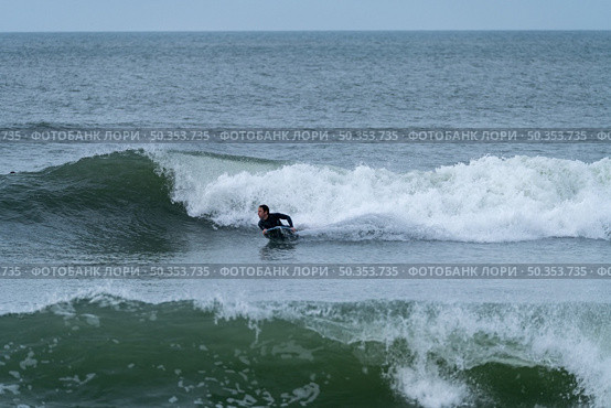 Bodyboarder performing a 360 trick surfing ocean wave on a cloudy winter day. Стоковое фото, агентство Ingram Publishing / Фотобанк Лори